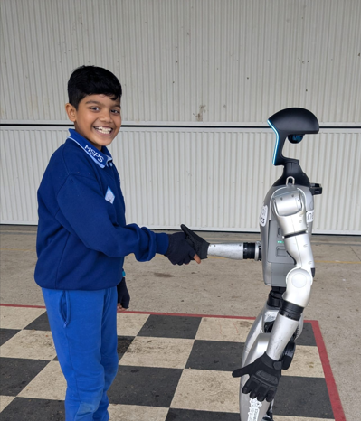 Photo of student shaking robot hand for STEM Team Amazon Event