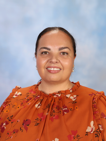 Photo of Marayong South Public Schools Principal, Tara Hosking. She is smiling and is characterised by brown hair, brown eyes and an orange blouse.